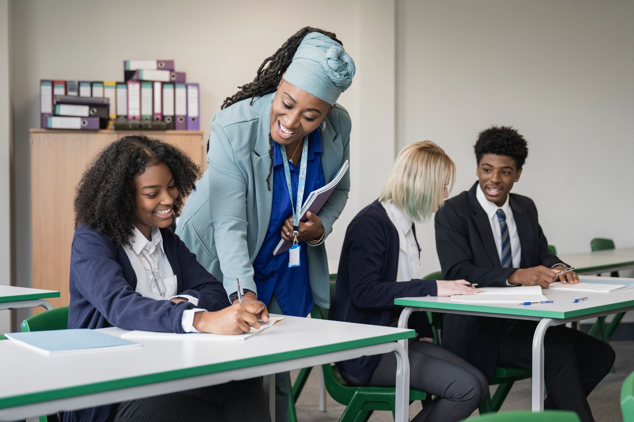 Educator supporting students with writing in a classroom