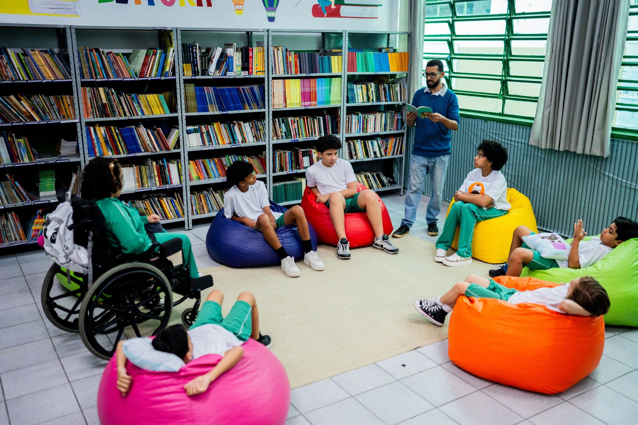Teacher reading aloud to a diverse group of children in a school library