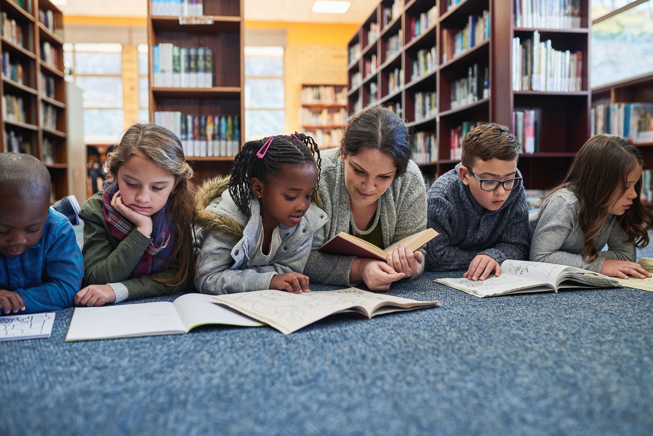 Children and a teacher working together in a school library